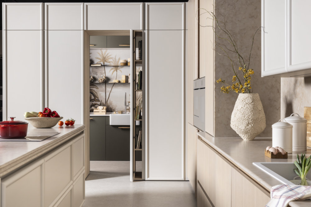 Cocina con muebles de líneas limpias, tonos neutros y detalles decorativos como flores y una vajilla elegante.